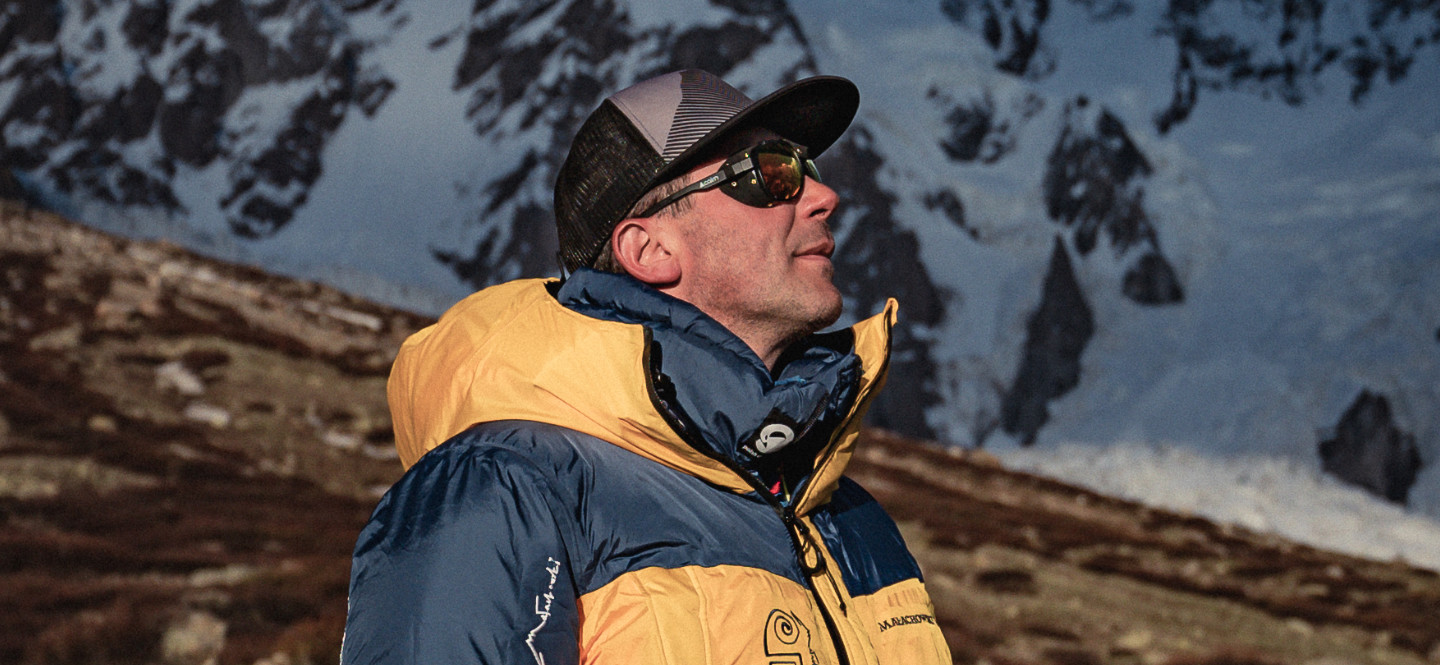 Na zdjęciu mężczyzna w zimowej kurtce stojący pośród gór